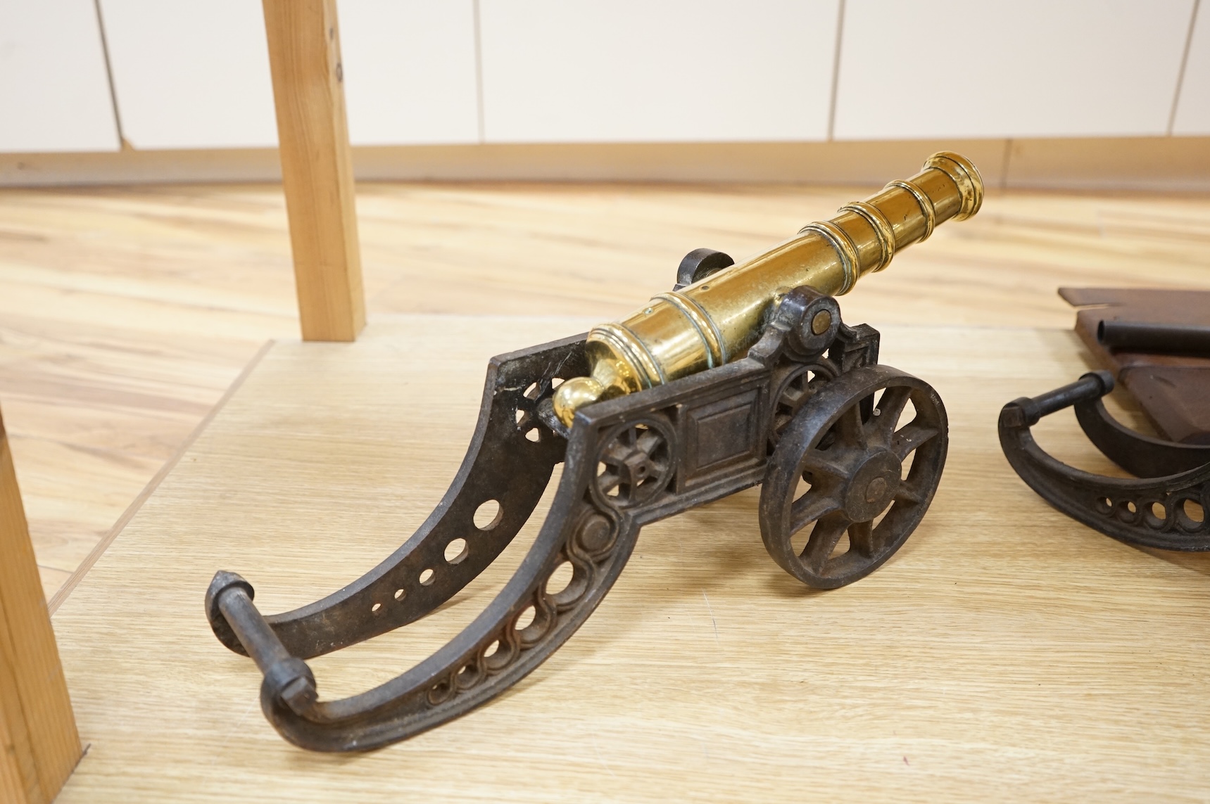 A decorative pair of brass model cannons, with turned barrels, 29cm overall, on cast iron pierced carriages with pierced wheels, overall length 46cm